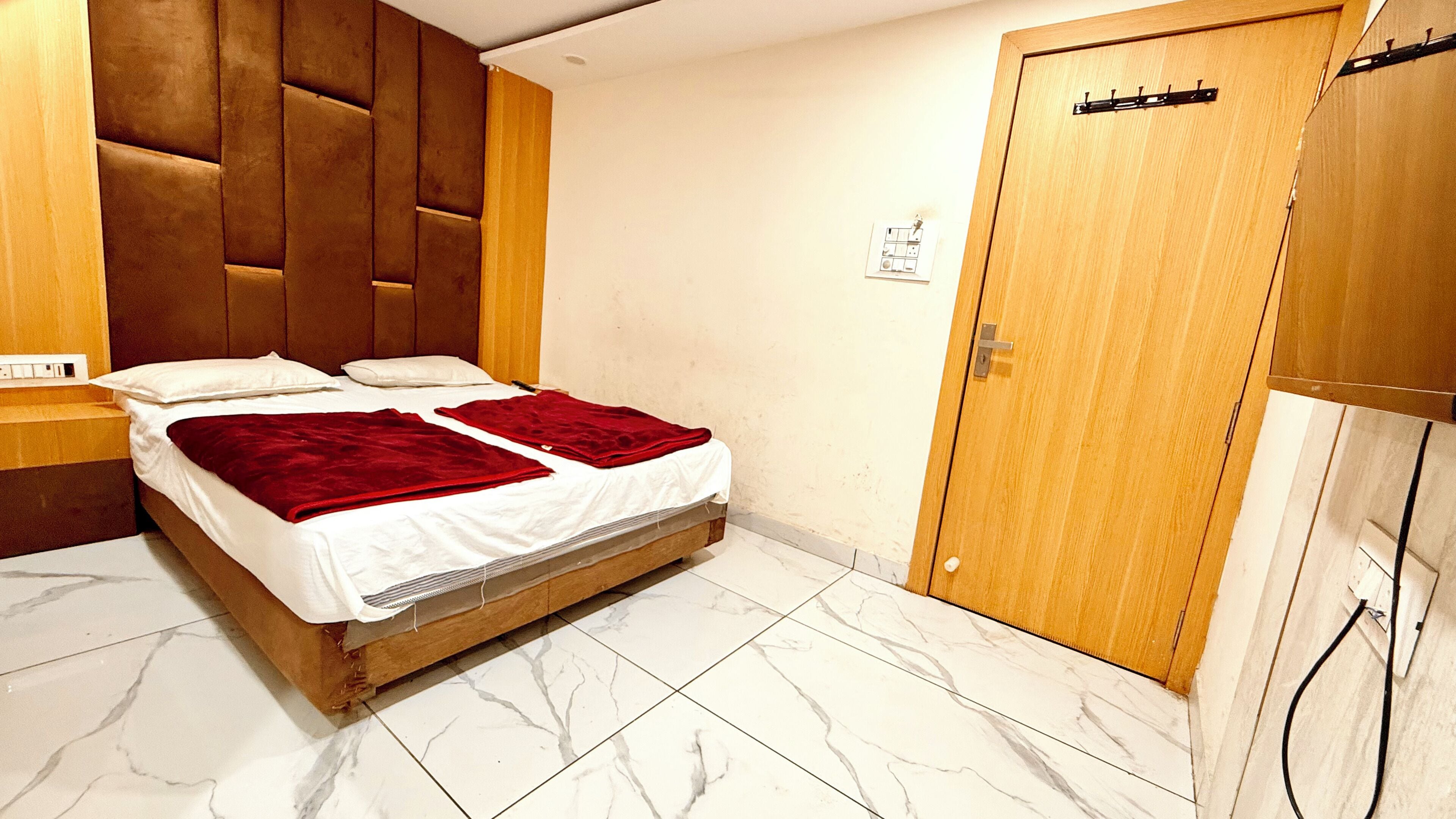 Een slaapkamer met een bed, een houten garderobe en een marmeren vloer.