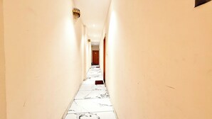 Un pasillo estrecho con paredes blancas y suelo de mármol.