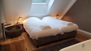 A bedroom with a stone basin, two beds with towels, a skylight, and a bathtub. - Luxurious 2-person apartment (Leidschendam)