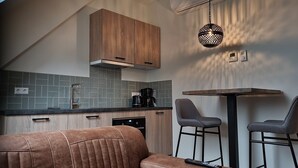 Una cocina moderna con un mueble de madera, una cafetera y una lámpara colgante.