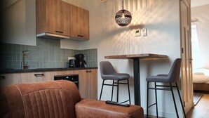 Una cocina moderna con armarios de madera, una cafetera y un comedor con una mesa y dos sillas.