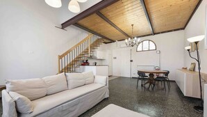Amplia sala de estar con sofá, mesa de comedor y cocina al fondo.