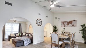 A spacious living room with a sofa set, a dining table with chairs, and a large world map on the wall.