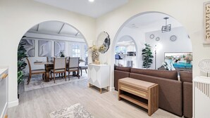 A modern living room with a sofa, coffee table, and dining area with chairs and a table.