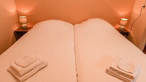 A double bed with two nightstands, each with a lamp, and towels on the bed.
