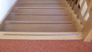 A wooden staircase with a handrail and carpeted steps.