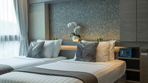 A modern hotel room with two beds, a patterned wall, a vase with flowers, and a small shelf with items. - Steps to Kamala Beach Rooftop Pool  C138 (Kamala)