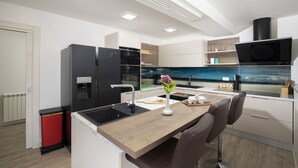 A modern kitchen with a wooden countertop, black appliances, and a view of the city through a window. - Holiday Estate Stancija Matošić in Medulin (Medulin)