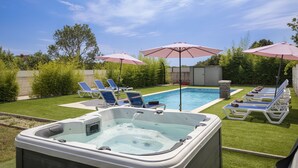 A backyard with a hot tub, a swimming pool, and lounge chairs under umbrellas. - Holiday Estate Stancija Matošić in Medulin (Medulin)
