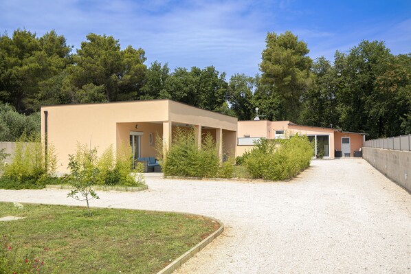 Un bâtiment à l’extérieur de couleur beige, avec une allée en gravier et une petite pelouse.