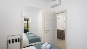 A hotel room with two beds, a mirror, a door leading to a living area, and an air conditioning unit. - Holiday Estate Stancija Matošić in Medulin (Medulin)