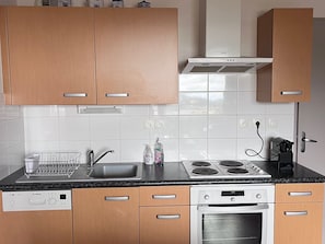 A modern kitchen with wooden cabinets, a Bosch dishwasher, a stove, and an oven. - Spacious apartment for 6 with terrace and private parking (Besse-et-Saint-Anastaise-Super Besse)
