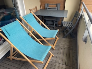 A wooden deck with two blue lounge chairs, a table, and chairs. - Spacious apartment for 6 with terrace and private parking (Besse-et-Saint-Anastaise-Super Besse)