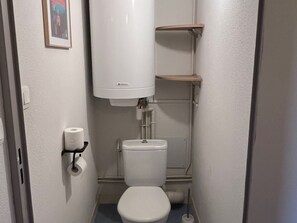 A small, compact bathroom with a toilet, a toilet paper holder, and a shelf above the toilet. - Spacious apartment for 6 with terrace and private parking (Besse-et-Saint-Anastaise-Super Besse)