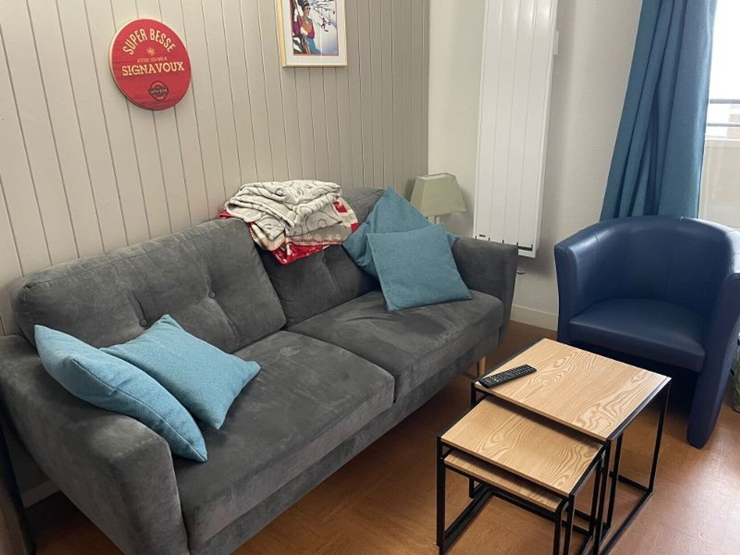 A living room with a grey sofa, two blue cushions, a small wooden table, and a blue armchair.