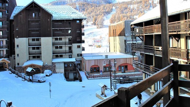 A snow-covered building with multiple balconies and a ski slope in the background. - Mountain studio 4 pers, South, Ski-in/out (Risoul)