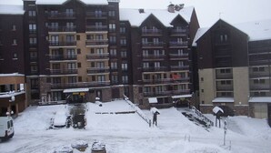 A multi-story hotel with balconies and a snow-covered parking area. - Mountain studio 4 pers, South, Ski-in/out (Risoul)