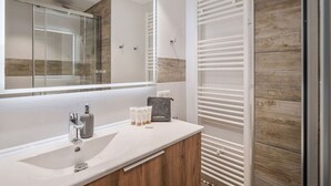 A modern bathroom with a large mirror, a sink, and a shower area. - Family duplex near Courchevel slopes with wifi and parking (Courchevel 1650)