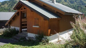 Una cabana de fusta amb teulada inclinada, una xemeneu i un petit porxo.