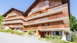 Un edifici de fusta de diversos pisos amb balcons i una pista d'esquí al fons.