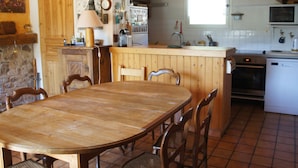 Cuina amb armaris de fusta, taula de dinar, cadirees, fogó i microones.