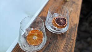 Una bañera con dos vasos transparentes llenos de agua y rodajas de naranja deshidratada.