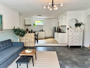 Un salon moderne avec un canapé gris, une table basse et un mur d’accent en pierre.