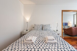Ett sovrum med en säng, två sänglampor, en tv och en brun läderfåtölj.
