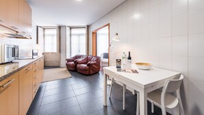 Eine moderne Küche mit Essbereich, ausgestattet mit einer Couch, einem Tisch mit Stühlen und einem großen Fenster für natürliches Licht.