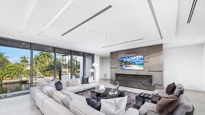 A modern living room with a large sofa, a coffee table, and a TV mounted on the wall.