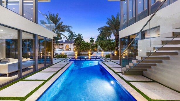 A modern pool area with glass walls, a clear blue pool, and a staircase leading to an upper level.