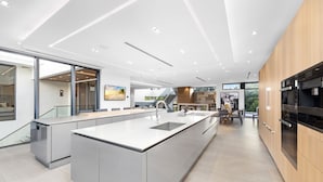 A modern kitchen with a large island, built-in appliances, and a view to the outdoors.