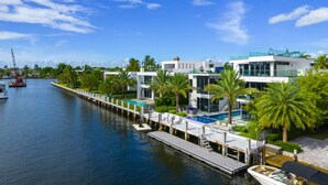 A waterfront property with modern architecture, a swimming pool, and a dock with boats.