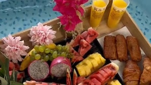 Eine Schale mit verschiedenen Früchten, Gebäck und Saftgläsern auf einem Tisch.