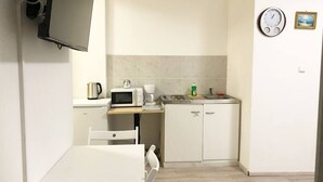 Een kleine keuken met een magnetron, koffiezetapparaat en een klein spoelbakje.