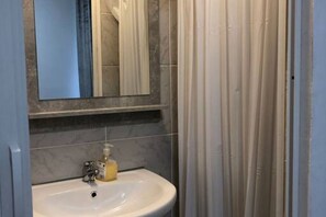 Een badkamer met een wit wastafel, een spiegel en een douchegordijn.