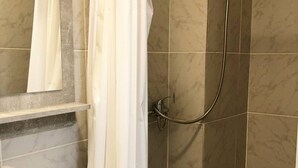 Een badkamer met een douche, een wit wastafelmeubel en een spiegel.