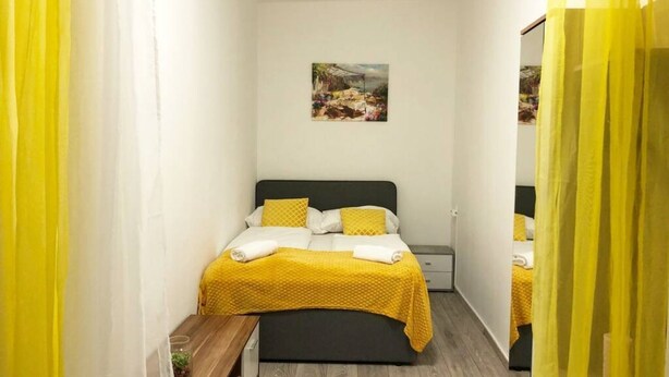 Een slaapkamer met een bed, een nachtkastje, een spiegel en een schilderij aan de muur.