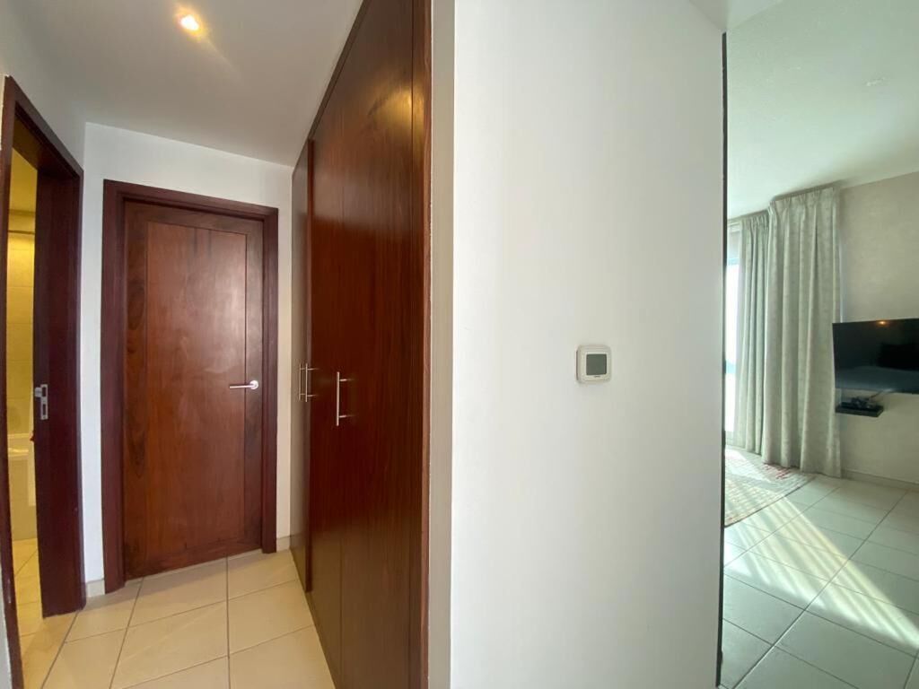 A hallway with a wooden door and a thermostat on the wall.