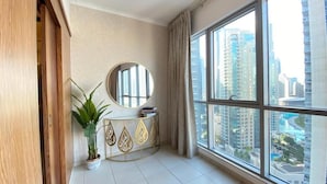 A spacious room with a large window offering a city view, a round mirror, a small plant, and a decorative console table. - Durrani Homes - The Residences 5BR Besides Dubai Mall with Burjkhalifa and Fountain view (Dubai)