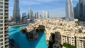 A high-rise building with a curved facade, surrounded by other tall buildings and a body of water. - Durrani Homes - The Residences 5BR Besides Dubai Mall with Burjkhalifa and Fountain view (Dubai)
