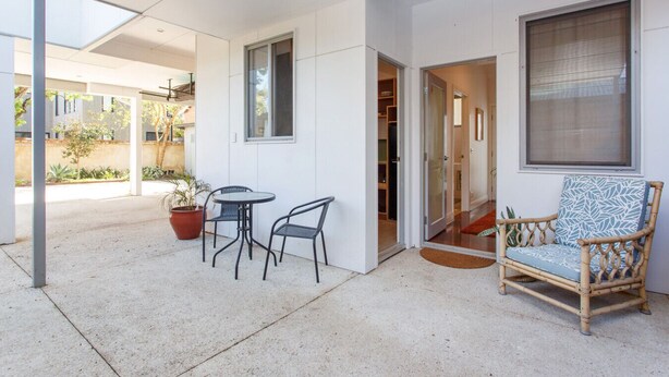 A covered patio area with a table and chairs, a wicker chair, and a potted plant. - Drift Studio - Cosy Fremantle Hideaway (Beaconsfield)