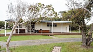 A single-story house with a porch, a small deck, and a brick pathway leading to the entrance.