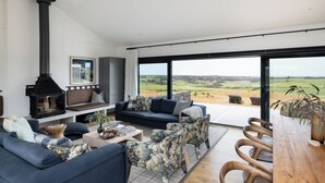Uma sala de estar moderna com uma janela grande, lareira, sofá e área de jantar.