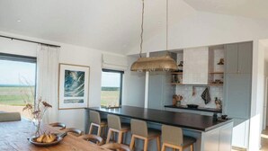 Cozinha moderna com ilha central, banquetas e vista para o exterior.