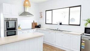A modern kitchen with white cabinetry, a large window, and a built-in oven.