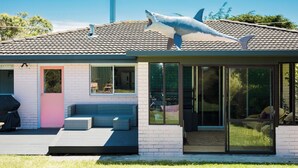 A modern house with a large shark sculpture on the roof, large windows, and a patio area. - The Shark Haus Summar (Peterborough)