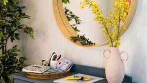 A blue dresser with a mirror, a vase with yellow flowers, and a plant. - The Shark Haus Summar (Peterborough)