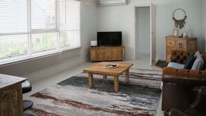 Un salon avec un téléviseur, un meuble en bois et un canapé en cuir marron.