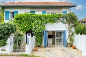 A two-story house with a white exterior, blue shutters, and a covered patio area.